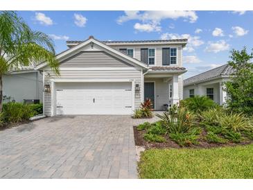 Two-story house with gray siding, white garage door, and landscaped yard at 2783 Butterfly Jasmine Trl, Sarasota, FL 34240