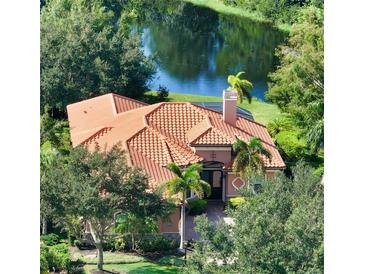 Beautiful aerial view of a house with a tile roof surrounded by lush greenery and overlooking a tranquil pond at 14636 Newtonmore Ln, Lakewood Ranch, FL 34202