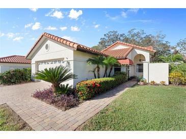 Spanish style home with tile roof, landscaping, and paved driveway at 4966 Clubview E Ct, Bradenton, FL 34203