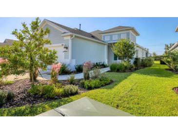 Charming single-Gathering home featuring a lush, landscaped front yard with vibrant flowers and green grass at 14611 Barefoot Ln, Parrish, FL 34219
