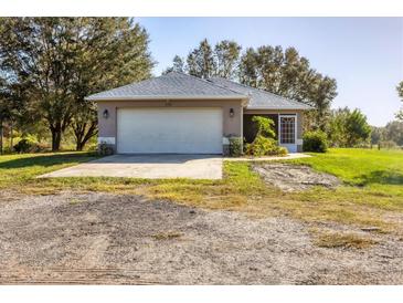 One-story home with a white garage door and screened porch at 424 Logue Rd, Myakka City, FL 34251