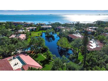 Aerial view of waterfront community with lush landscaping, pond, and bay access at 6466 Seagull Dr # 323, Bradenton, FL 34210