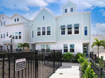 Light blue three-story townhome with a black fence and walkway at 2308 Lindstrom St, Sarasota, FL 34237