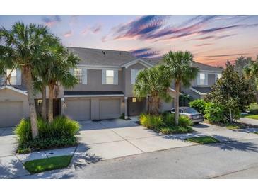 Charming townhome featuring a two-car garage, landscaped yard, and front yard with mature palm trees at 14879 Skip Jack Loop, Lakewood Ranch, FL 34202