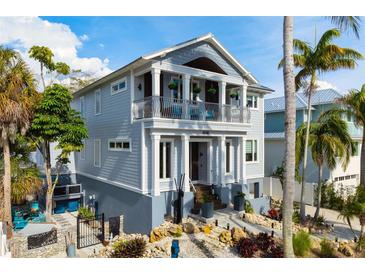 Two story home with balcony and landscaped yard, featuring gray siding at 6940 Longboat S Dr, Longboat Key, FL 34228