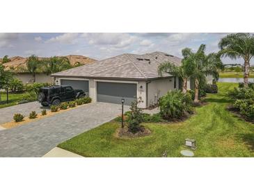 Luxury home with a three-car garage, a well-maintained lawn, and palm trees at 15967 Clear Skies Pl, Lakewood Ranch, FL 34211