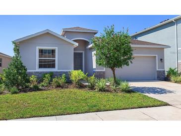 Single-story home with gray exterior, landscaping and two-car garage at 5719 Woodland Sage Dr, Sarasota, FL 34238