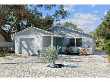Charming single-story home featuring a well-maintained front yard with stone landscaping and a turquoise front door at 1105 58Th S St, Gulfport, FL 33707