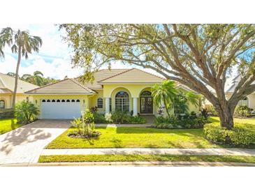 Beautiful yellow home with lush landscaping and a large tree at 7506 Eaton Ct, University Park, FL 34201