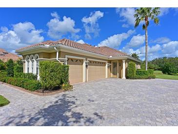 Stunning home showcasing lush landscaping, a paver driveway, a barrel tile roof, and a three-car garage at 10209 Discovery Ter, Bradenton, FL 34212