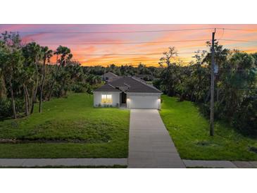 Stunning single-story home with a well-manicured lawn and a long driveway, at sunset at 1800 S San Mateo Dr, North Port, FL 34288