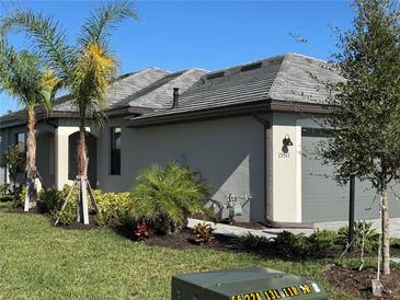 Single-story home with gray exterior, landscaped yard, and palm trees at 15511 Sunny Day Dr, Lakewood Ranch, FL 34211