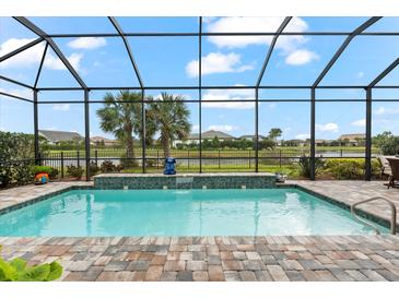 Inviting screened pool with brick pavers, lush landscaping, and beautiful water view for ultimate relaxation at 17802 Eastbrook Ter, Lakewood Ranch, FL 34202