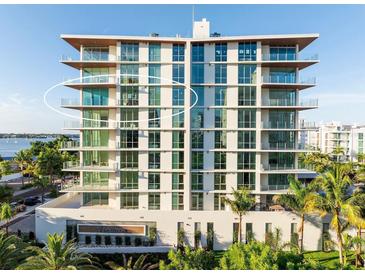 A modern condo building with floor to ceiling windows and balconies on a sunny day near the water at 111 Golden Gate Pt # 602, Sarasota, FL 34236