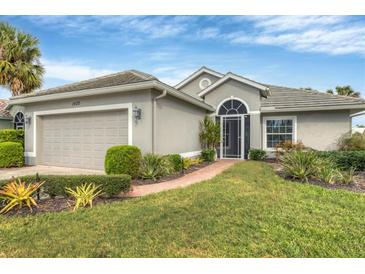 Single-story house with gray siding, two-car garage, and manicured lawn at 1420 Turnberry Dr, Venice, FL 34292