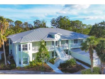 Aerial view of a two-story light green building with a metal roof, surrounded by lush tropical landscaping at 294 Hidden Bay Dr # 203, Osprey, FL 34229