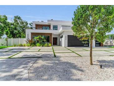 Modern two-story home featuring a black garage door, a balcony, and landscaping at 2038 Datura St, Sarasota, FL 34239