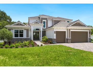 Two-story home with a three-car garage, stone accents, and landscaped lawn at 1637 Hyde Park St, Sarasota, FL 34239