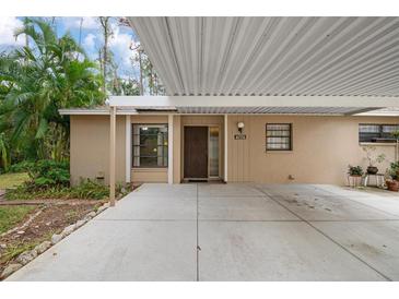 Tan house exterior with carport and lush landscaping at 4773 Village Gardens Dr # 97, Sarasota, FL 34234