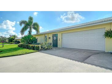 Front view of a yellow house with a white garage door and landscaping at 3712 Hampshire Ln # 5623, Sarasota, FL 34232