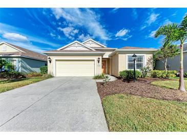 Tan one-story house with a two-car garage and landscaped yard at 1422 Blue Horizon Cir, Bradenton, FL 34208