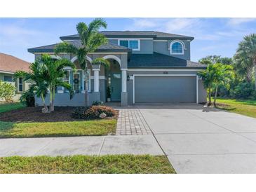 Charming two-story home with palm trees, a well-manicured lawn, and a two-car garage at 1868 Scarlett Ave, North Port, FL 34289