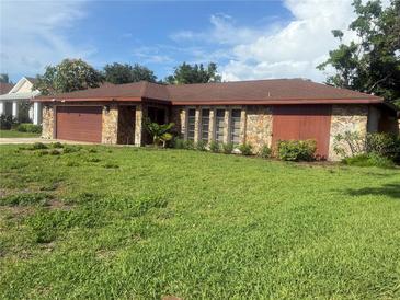Charming single-story home featuring a stone facade, lush green lawn and a brown garage door at 117 Hillcrest Dr, Bradenton, FL 34209