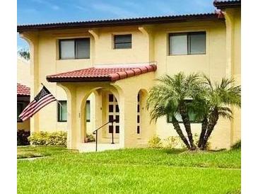 Tan building exterior with red tile roof, lush landscaping, and American flag at 1446 56Th W St # 1446, Bradenton, FL 34209