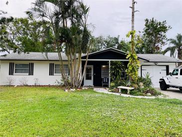 Ranch-style home with white exterior, black accents, and a lush lawn at 2549 Arapaho St, Sarasota, FL 34231