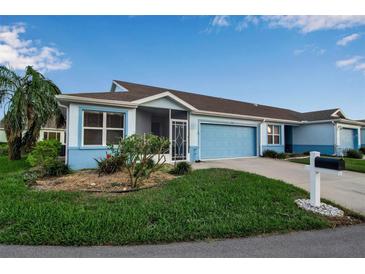 Front view of a light blue house with a two-car garage and well-maintained lawn at 3115 Live Oak Ln # 30, Palmetto, FL 34221