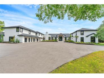 Stunning white home with black trim, multi-car garage, circular driveway, and manicured landscaping at 2410 Slough Rd, Sarasota, FL 34240