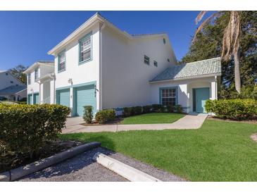 Two-story condo with teal accents, attached garage, and landscaped lawn at 6591 Fairway Gardens Dr # 2-102, Bradenton, FL 34203