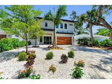 Modern two-story home featuring a manicured front yard with decorative white rock, landscaping, and paver driveway at 2425 Floyd St, Sarasota, FL 34239