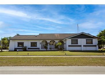 White single-story home with dark gray accents, tile roof, and a well-manicured lawn at 2711 W Marion Ave, Punta Gorda, FL 33950