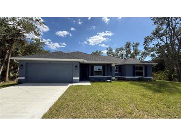 Charming single-story home featuring a two-car garage, well-manicured lawn, and stylish architectural details at 3249 Vickers Ln, North Port, FL 34286