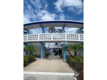 The Dorset: Exterior view of building, showing walkway, landscaping, and unique architectural details at 475 Benjamin Franklin Dr # 202, Sarasota, FL 34236