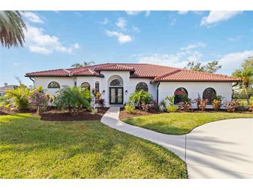White house with red tile roof, landscaping, and a paved driveway at 5156 Little Brook Ct, Sarasota, FL 34238