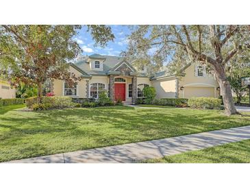 Beautiful one-story home with a red door, lush landscaping, and a large green lawn at 9506 Royal Calcutta Pl, Lakewood Ranch, FL 34202