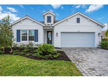 White house with blue shutters, landscaped yard, and paver driveway at 10180 Canaveral Cir, Sarasota, FL 34241