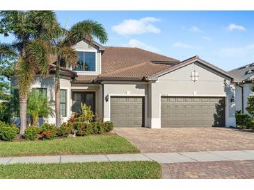 Two-story house with three car garage, landscaping, and brick driveway at 12432 Golden Sage Dr, Sarasota, FL 34238