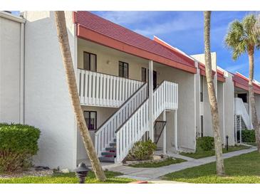 White building with red roof, stairs, and palm trees at 1801 Gulf N Dr # 222, Bradenton Beach, FL 34217
