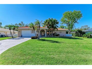 Charming home with a well-manicured lawn and tropical landscaping at 220 Monet Dr, Nokomis, FL 34275