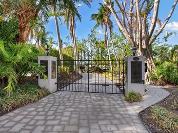 Paved driveway leading to a gated entrance lined with tropical landscaping at 3460 Flamingo Ave, Sarasota, FL 34242