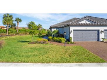 Charming single-story home featuring a well-manicured lawn, lush landscaping, and a brick-paved driveway leading to a two-car garage at 4705 Tortona Ct, Bradenton, FL 34211