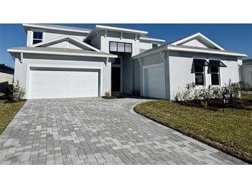 Two-story home with gray exterior, white garage doors, and paver driveway at 8324 Golden Beach Ct, Parrish, FL 34219