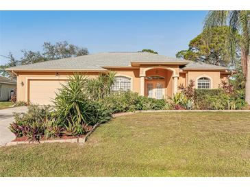 Tan house with gray roof, two-car garage, and landscaped yard at 3623 Monday Ter, North Port, FL 34286