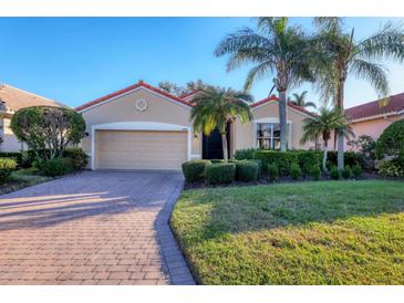 Tan one-story house with a two-car garage and lush landscaping at 4210 65Th E Ter, Sarasota, FL 34243