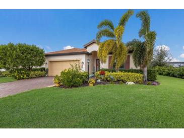 Single-story home with landscaped yard, palm trees, and brick driveway at 10233 Loch Lomond Dr, Bradenton, FL 34211