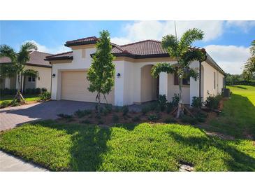 Single-story home with tile roof, two-car garage, and landscaped yard at 24157 Spartina Dr, Venice, FL 34293