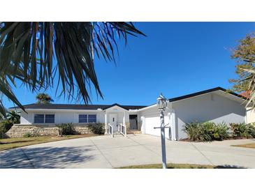 White single-story home with a black roof, attached garage, and palm trees at 1732 Boca Raton Ct, Punta Gorda, FL 33950